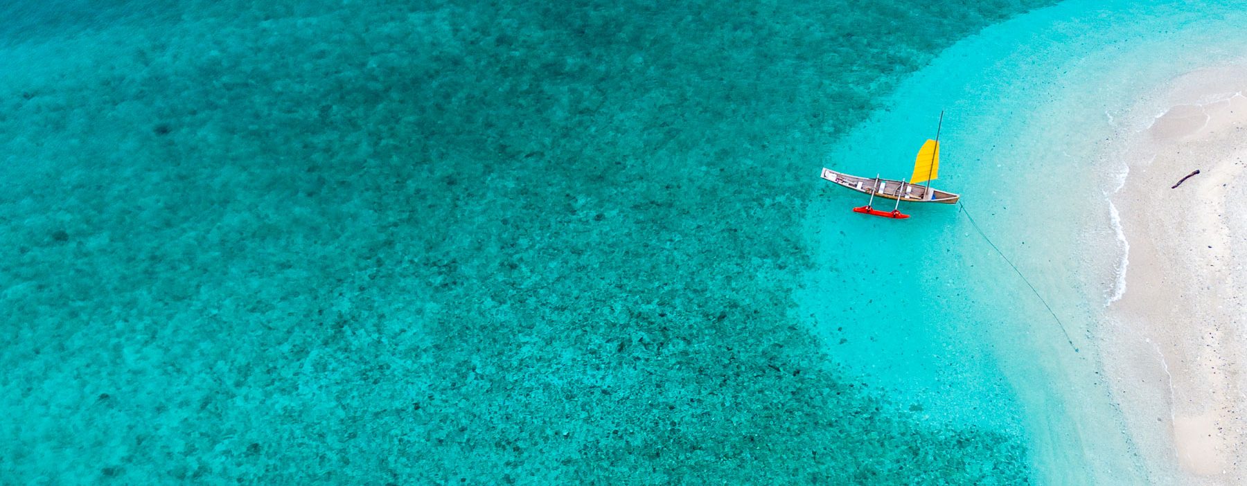 Bateau à voile coloré en mer turquoise.
